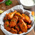 Homemade crispy buffalo chicken wings with hot sauce and ranch dip, served with celery sticks on wooden table